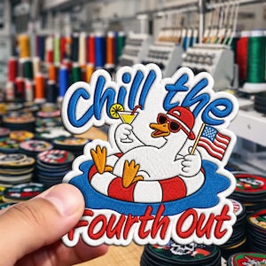 May include: Embroidered patch featuring a cartoon duck in sunglasses and a red hat, relaxing in a pool float with a cocktail and an American flag. The patch reads "Chill the Fourth Out" in blue and red.