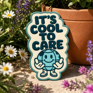 May include: An embroidered patch with a cream-colored background and a teal border. The text reads IT'S COOL TO CARE in dark teal letters. Below the text is a light blue globe character with a smiling face, arms, and legs in dark teal.