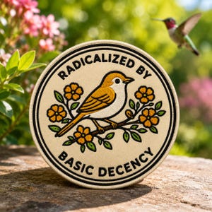 May include: A circular embroidered patch with a cream background featuring a yellow and white bird perched on a branch with orange flowers and green leaves. The text RADICALIZED BY BASIC DECENCY is stitched in black along the top and bottom edges.
