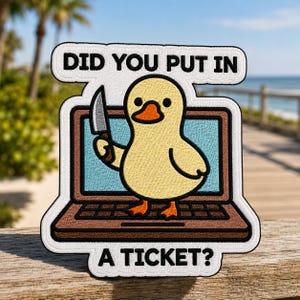 May include: An embroidered patch featuring a yellow duck holding a silver knife while standing on a brown laptop. The text above reads DID YOU PUT IN and the text below reads A TICKET? The patch has a white border and a light blue screen background.