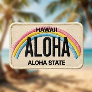 May include: A rectangular embroidered patch with a cream-colored background. It features a rainbow arching over the black text ALOHA. Above the rainbow is the word HAWAII, and below the rainbow is the text ALOHA STATE, all in black embroidery.