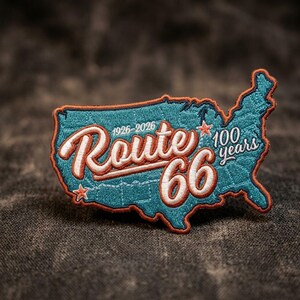 May include: Embroidered patch in the shape of the United States, featuring the text "Route 66" in a vintage style. The patch is teal with orange and white accents, celebrating 100 years of Route 66 from 1926-2026.