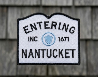 May include: A white patch with a black border and the words "ENTERING NANTUCKET" in black. The patch also includes "INC 1671" and a light blue emblem.