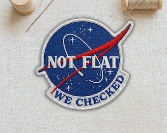 May include: Embroidered patch with a blue background, white stars, and a red swoosh design. The patch reads "NOT FLAT WE CHECKED" in white lettering. Two spools of thread and a needle are in the background.