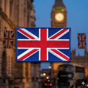 May include: A rectangular patch featuring the Union Jack, the national flag of the United Kingdom. The flag design includes red and white diagonal and vertical stripes on a blue background. The patch is set against a blurred background of London landmarks.
