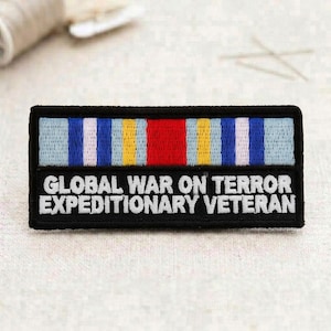 May include: A black embroidered patch with the text "GLOBAL WAR ON TERROR EXPEDITIONARY VETERAN" in white. Above the text are embroidered ribbons in red, blue, yellow, and white. The patch is rectangular and has a black border.