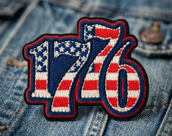 May include: An embroidered patch in the shape of the number 1776, featuring a red, white, and blue American flag pattern. The patch has a thick black border and is stitched with white stars on a blue background and horizontal red and white stripes.