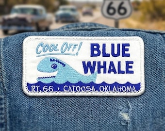 May include: A rectangular embroidered patch on blue denim fabric featuring a light blue whale illustration, the text COOL OFF! BLUE WHALE, and the text RT. 66 CATOOSA, OKLAHOMA in blue and white thread with a white border and stitched edges.