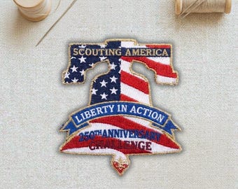 May include: Embroidered patch in the shape of the Liberty Bell, featuring the American flag design. The patch includes the text "SCOUTING AMERICA", "LIBERTY IN ACTION", and "250TH ANNIVERSARY CHALLENGE". A spool of thread and a needle are in the background.