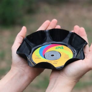 May include: A black vinyl record repurposed into a small dish. The record has a colorful label with the text "STICKY MAN FROM NOWHERE" and "STEREO".