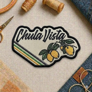 May include: Embroidered patch with the text "Chula Vista" in black script. The patch features a lemon branch with yellow lemons and green leaves. A black border surrounds the patch, with a striped design of yellow, green, and gray.