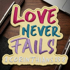 May include: Embroidered patch with the words "LOVE NEVER FAILS" in pink, teal, and purple, with the Bible verse "1 Corinthians 13:8" in white. The patch has a yellow background and a decorative border.