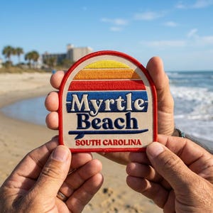 May include: A semi-circular embroidered patch with a red border featuring a sunset graphic in yellow, orange, and red stripes above the dark blue text Myrtle Beach and South Carolina, with a dark blue surfboard icon underlining the text.