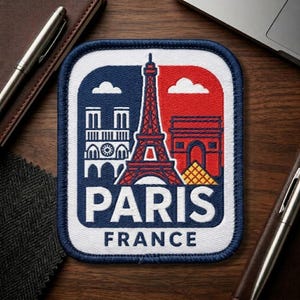 May include: Embroidered patch featuring iconic Paris landmarks: the Eiffel Tower, Notre Dame, and Arc de Triomphe. The patch has a blue, red, and white color scheme with the word "PARIS" and "FRANCE" in white lettering. The patch is rectangular with rounded corners.