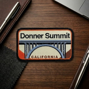 May include: Rectangular patch with the words "Donner Summit" and "California" in a retro design. The patch features a bridge illustration in blue, orange, and brown, with a black border.