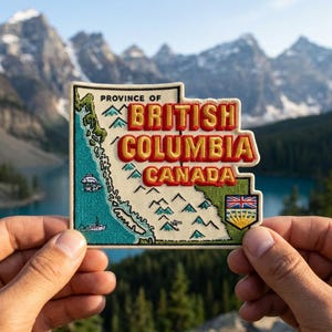 May include: An embroidered patch shaped like the province of British Columbia, Canada. The design features a cream-colored map with teal coastlines, small blue mountain icons, a fish, a boat, and the red and yellow text PROVINCE OF BRITISH COLUMBIA CANADA.