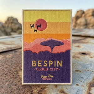 May include: Embroidered patch featuring a sunset scene with a red sun, two black TIE fighters, and a cloud city silhouette. The patch reads "BESPIN - CLOUD CITY - Outer Rim Territories" in gold lettering against a purple background.