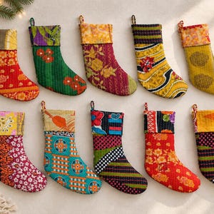 May include: Ten Christmas stockings arranged in two rows, each featuring unique, vibrant, multi-colored fabric patterns with visible stitching. The stockings display various floral, geometric, and abstract designs in shades of red, green, yellow, blue, and pink, all equipped with a small fabric loop at the top for hanging.