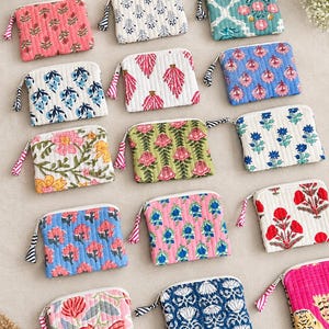 Puede incluir: Una colección de catorce estuches rectangulares acolchados con cremallera, con diversos estampados florales y botánicos en colores como rosa, azul, verde, rojo y blanco. Cada estuche tiene un pequeño tirador de tela en la cremallera.