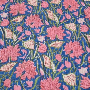 May include: A blue floral quilt with a repeating pattern of pink lotus flowers and white leaves. The quilt is stitched with white thread, creating a textured effect. The design is a mix of floral and botanical elements.