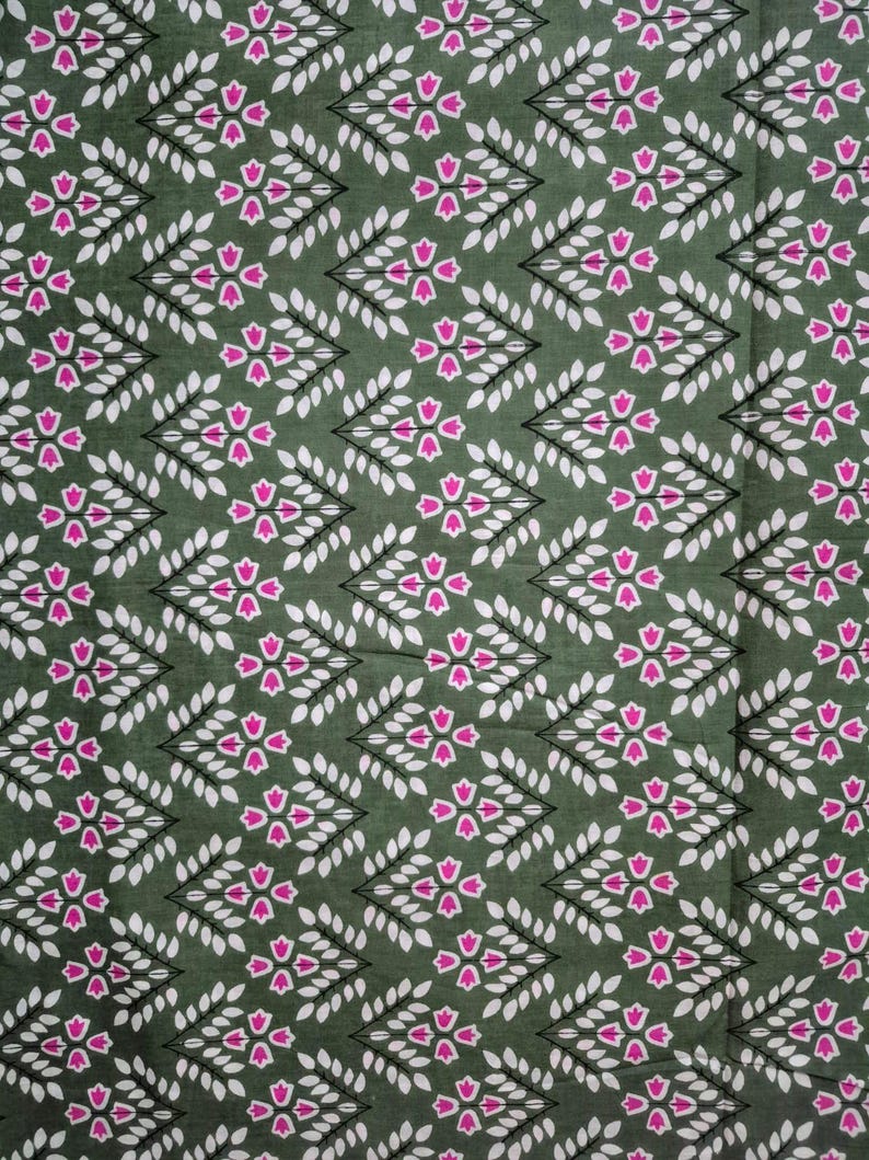 May include: A close-up of a fabric with a repeating pattern of white leaves and pink floral shapes on a dark green background. The design is arranged in diagonal rows, creating a textured appearance.