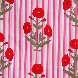 May include: A textile with a repeating pattern of red poppy flowers and green leaves on a striped background of pink, white, and beige. The floral design is centered on the fabric.