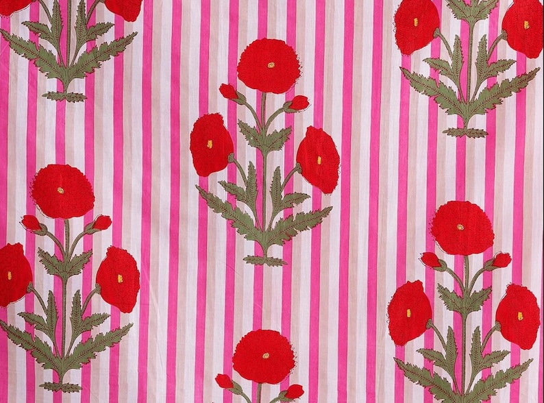 May include: A textile with a repeating pattern of red poppy flowers and green leaves on a striped background of pink, white, and beige. The floral design is centered on the fabric.