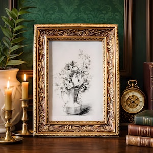 Op de afbeelding: Een rechthoekige, sierlijke gouden fotolijst met een bloemmotief omlijst een zwart-witte schets van bloemen in een vaas. Twee brandende kaarsen in gouden kandelaars en een gouden klok zijn ook zichtbaar.