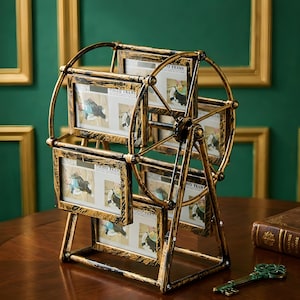 May include: A decorative, antique-style photo frame in the shape of a Ferris wheel. The frame is made of gold-colored metal and holds multiple photos. The words "PHOTO FRAME" are visible on the frames. A decorative key is on the table.