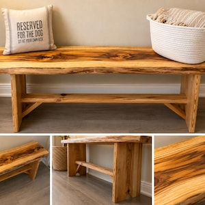 May include: A natural wood bench featuring a live edge top with prominent dark grain patterns and knots. The bench is supported by two sturdy vertical legs connected by a horizontal stretcher bar, showcasing a smooth, polished finish throughout.