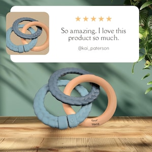 May include: Three interlocking teething rings in shades of blue and peach, resting on a wooden surface. The rings have a textured design and are connected with a clasp. The image includes text that says "So amazing. I love this product so much."