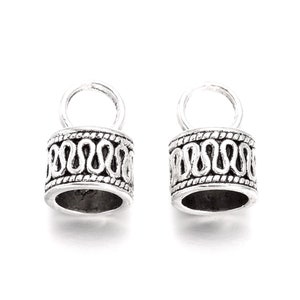 May include: Two silver metal cord end caps with a decorative design. Each cap has a small loop at the top.