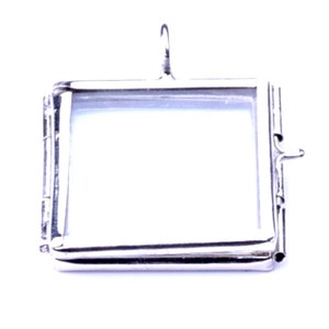May include: Silver locket pendant with a square glass window. The locket has a hinged opening and a loop for attaching a chain.