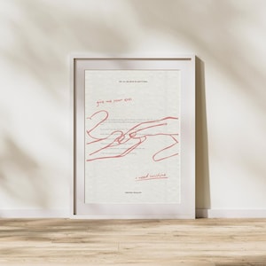 May include: A framed art print with a white border. The artwork features red line art of hands and text that reads "give me your eyes" and "I need sunshine". The background is a textured off-white.