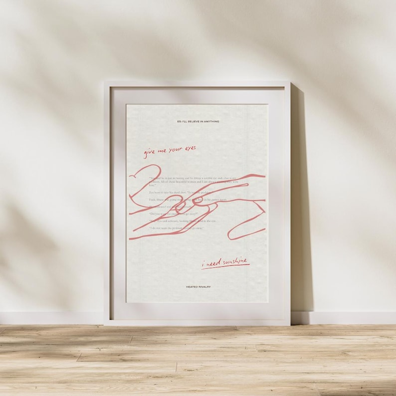 May include: A framed art print with a white border. The artwork features red line art of hands and text that reads "give me your eyes" and "I need sunshine". The background is a textured off-white.
