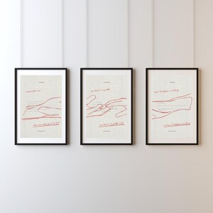 May include: Three framed art prints with black frames. Each print features a minimalist red line drawing and text on a cream background. The prints are hung on a white wall. The text includes phrases like "smile of the man" and "can think I'm pretty".
