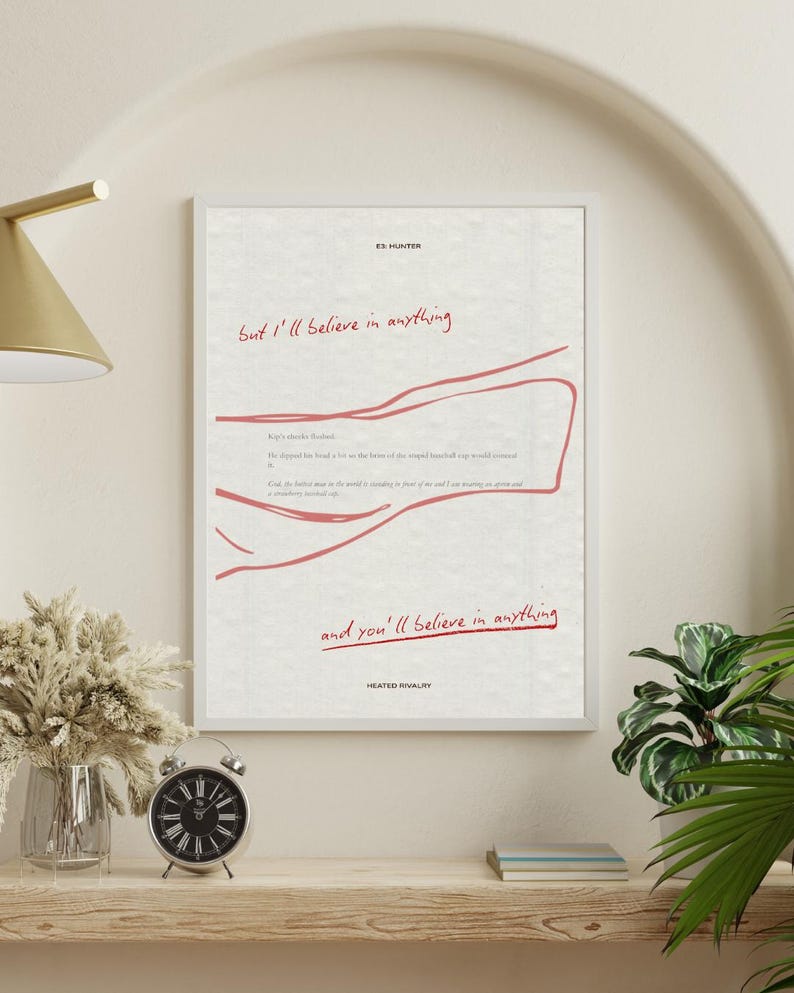 May include: A framed art print featuring the text "But I'll believe in anything" in red script. The print also includes a red line drawing and the text "and you'll believe in anything". The print is displayed on a wooden shelf with a clock and vase.