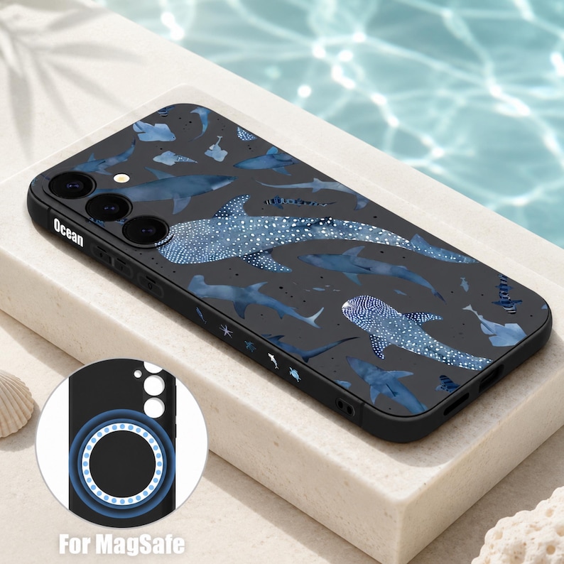May include: A black smartphone case featuring a pattern of blue whale sharks and various other sharks on the back. The side of the case displays the word Ocean. An inset circle shows the interior of the case with a blue magnetic ring for MagSafe.