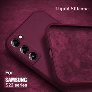 May include: Burgundy liquid silicone phone case for the Samsung S22 series. The case is shown in two parts, with the text "Liquid Silicone" and "For SAMSUNG S22 series" visible. The case has a soft, matte finish and is designed to protect the phone.