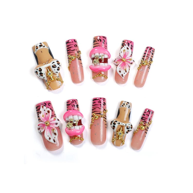 May include: A set of ten press-on nails featuring a variety of designs including pink tiger stripes, nude bases with leopard print bikini motifs, 3D pink lips with teeth, and white and pink floral accents, all embellished with gold beads and charms.