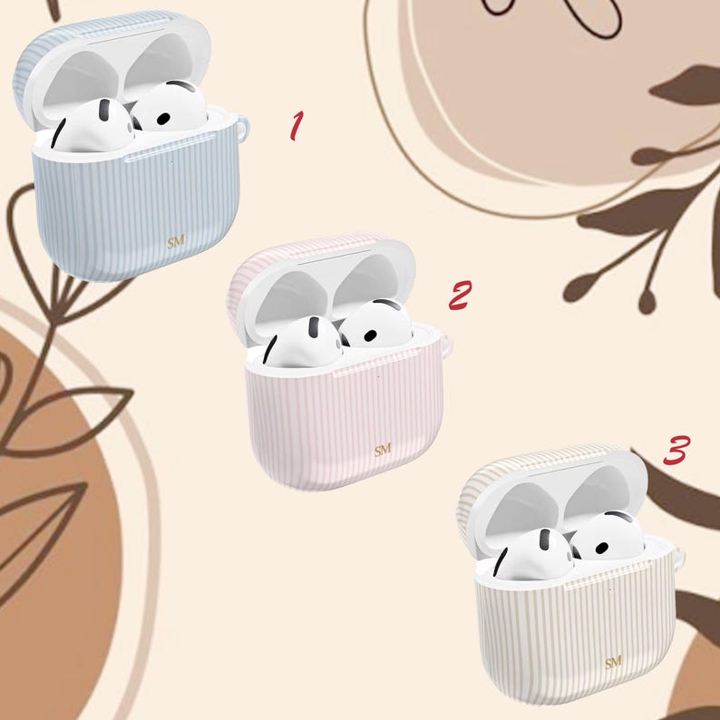 May include: Three open AirPod cases in pastel colors: light blue, pink, and cream. Each case has vertical stripes and contains white AirPods. The cases are labeled with "SM" and are set against a neutral background with floral accents.