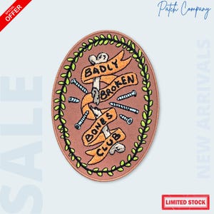 May include: An oval-shaped patch with a tan background, featuring a design with the words "BADLY BROKEN BONES CLUB" on orange banners. The design includes bones, screws, and a green leafy border. The patch has the text "LIMITED STOCK".