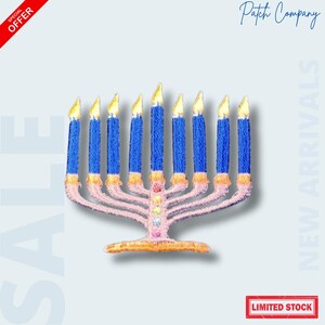 May include: Embroidered patch of a menorah with blue candles and yellow flames. The base and arms are pink, with gold accents. The patch has the text "LIMITED STOCK" in a red box.