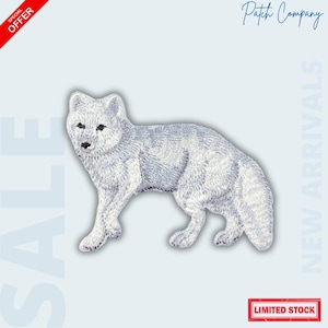 May include: Embroidered patch of a white arctic fox in a standing pose. The patch has detailed stitching, with black eyes and nose. The background is light blue with text that reads "SALE", "NEW ARRIVALS", and "LIMITED STOCK".