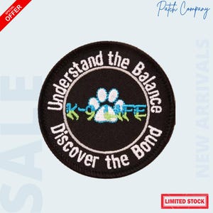 May include: A round black patch with white text that reads "Understand the Balance" and "Discover the Bond." The center features a paw print and the text "K-9 LIFE" in blue and green. The patch has a "Special Offer" banner.