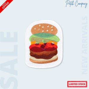 May include: Embroidered patch featuring a colorful burger design. The patch includes a sesame seed bun, lettuce, tomato, and a meat patty. The patch is on a white background with the words "SALE", "NEW ARRIVALS", and "LIMITED STOCK".