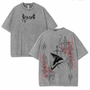 Puede incluir: Camiseta gris con diseño gótico. La parte delantera presenta la palabra "STRØME" sobre una cruz. La parte trasera muestra un cuervo negro posado en una rama, con patrones de cruces y florales ornamentados en rojo y negro. La camiseta tiene mangas cortas.