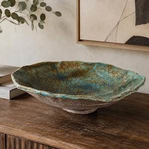 May include: A wide, shallow ceramic bowl with an irregular, organic rim. The interior features a vibrant turquoise and teal glaze with a dark, honeycomb-like hexagonal pattern. The exterior has a rough, textured, earthy brown finish.