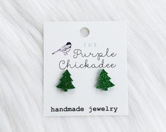 May include: A pair of green glitter Christmas tree earrings on a white card with the text "THE Purple Chickadee handmade jewelry".