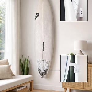 Könnte beinhalten: Ein weißes Surfbrett, das vertikal mit einem speziellen Befestigungssystem an einer Wand montiert ist. Das Brett zeigt schwarze Schriftzüge und ein strukturiertes Tailpad. Zwei Detailansichten zeigen die Wandhalterung und die Drahtaufhängung.